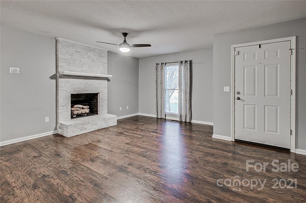 928 Meadowbrook Road Asheboro, NC 27203 - Photo 2 of 25 an empty room with wooden floor fireplace and windows