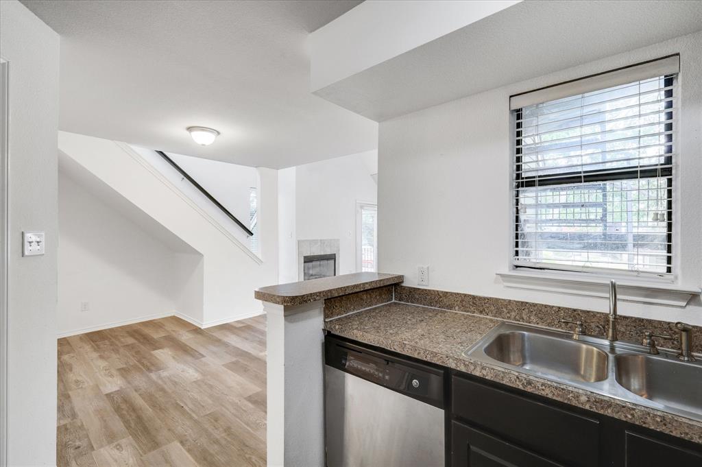 9831 Walnut Street, Unit 212 Dallas, TX 75243 - Photo 11 of 27 Kitchen with a fireplace, sink, stainless steel dishwasher, and light wood-type flooring