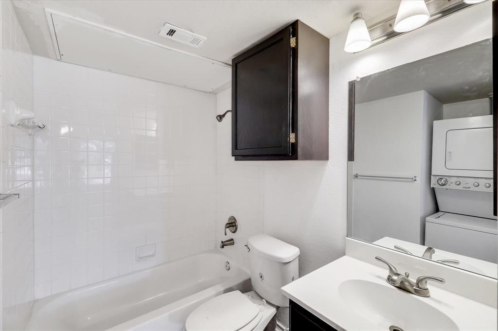 9831 Walnut Street, Unit 212 Dallas, TX 75243 - Photo 15 of 27 Full bathroom featuring vanity, toilet, tiled shower / bath, and stacked washer and clothes dryer