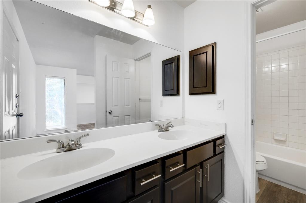 9831 Walnut Street, Unit 212 Dallas, TX 75243 - Photo 21 of 27 Full bathroom featuring vanity, hardwood / wood-style floors, tiled shower / bath, and toilet