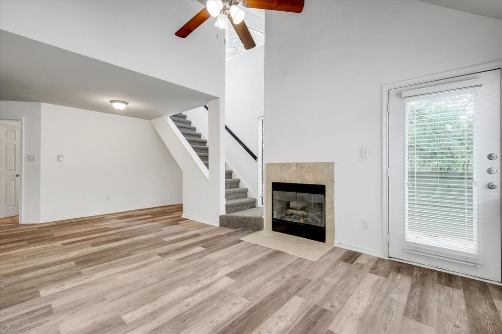 9831 Walnut Street, Unit 212 Dallas, TX 75243 - Photo 7 of 27 Unfurnished living room with ceiling fan, light wood-type flooring, high vaulted ceiling, and a tiled fireplace