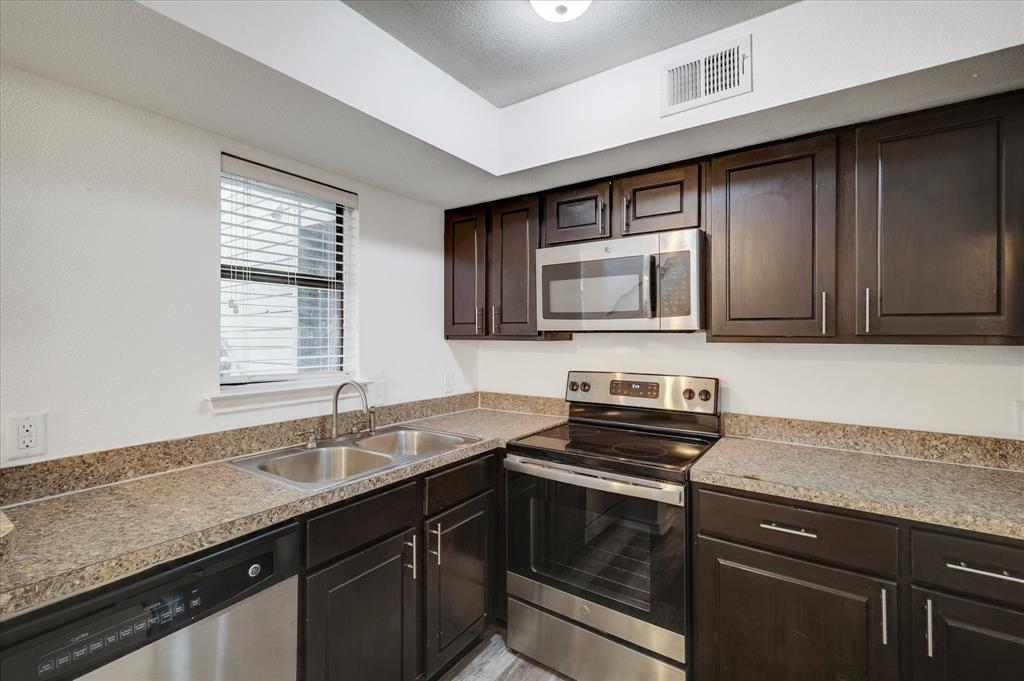 9831 Walnut Street, Unit 212 Dallas, TX 75243 - Photo 10 of 27 Kitchen featuring dark brown cabinetry, sink, stainless steel appliances, and a textured ceiling
