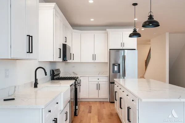 a kitchen with stainless steel appliances a refrigerator a sink a stove a microwave and wooden floor