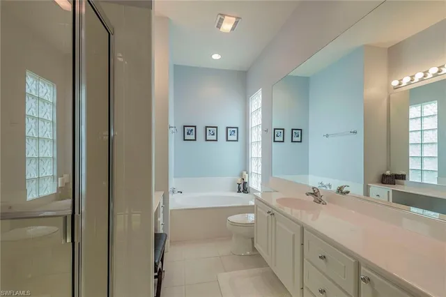a spacious bathroom with a double vanity sink toilet mirror and bathtub