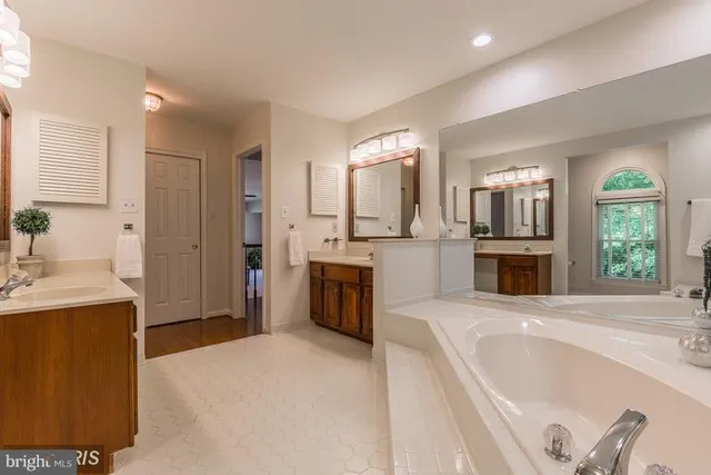 a large spacious bathroom with a tub double sink and mirror