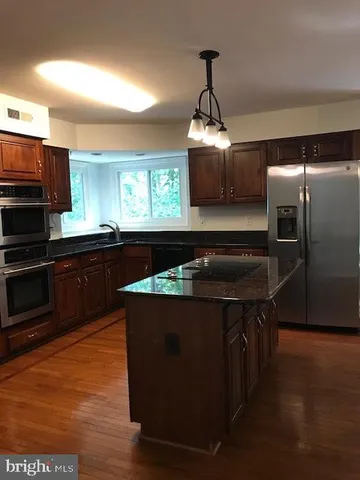 an empty room with wooden floor and windows with curtains