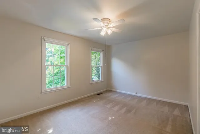 an empty room with windows and chandelier fan