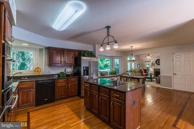 a kitchen with stainless steel appliances granite countertop wooden cabinets a stove and a sink