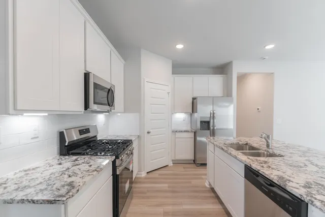 a kitchen with stainless steel appliances granite countertop a sink stove and refrigerator