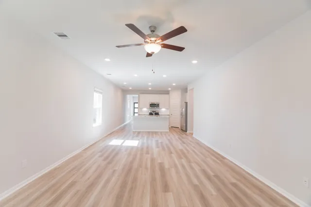 a view of an empty room with window and wooden floor