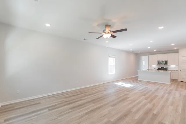 an empty room with windows and fan