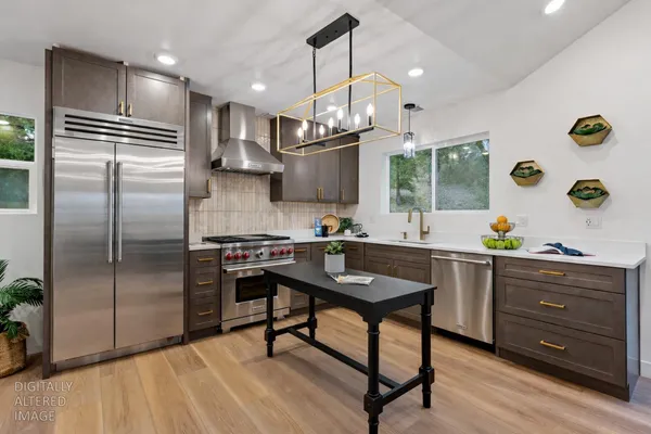 a kitchen with stainless steel appliances kitchen island granite countertop a sink a stove and a wooden floors