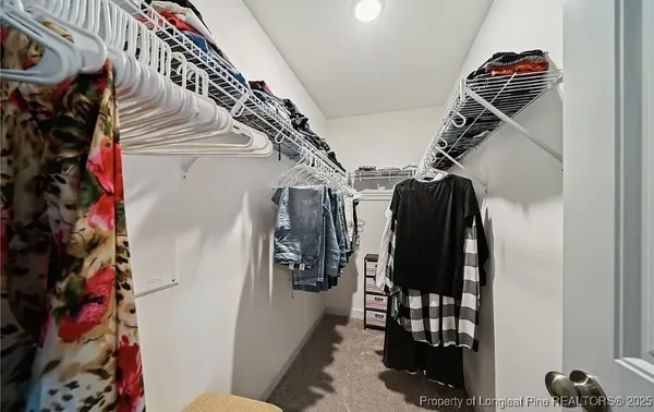 a view of walk in closet with clothes and shoes