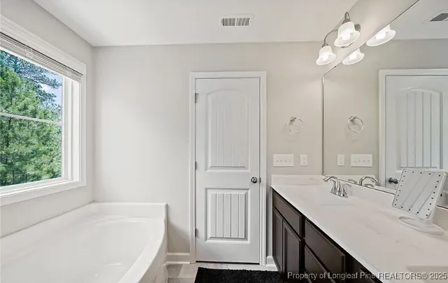 a bathroom with a tub a sink and a large mirror
