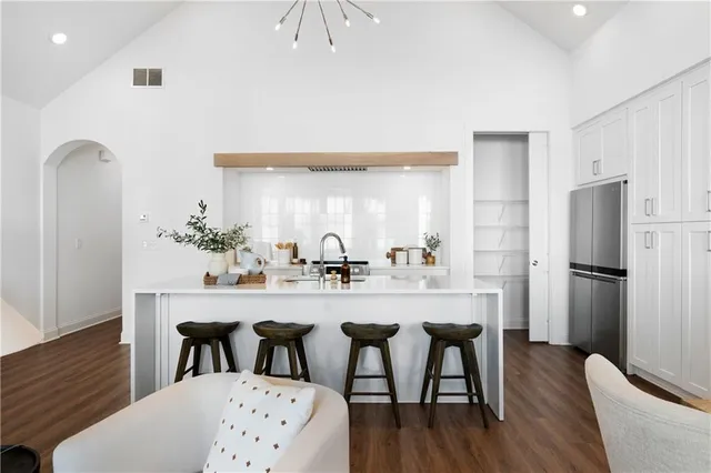 a kitchen with stainless steel appliances granite countertop a dining table chairs refrigerator and sink