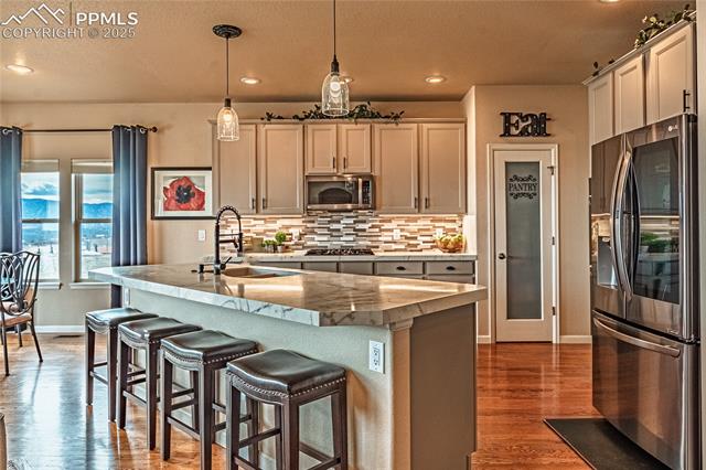 13812 Windy Oaks Road Colorado Springs, CO 80921 - Photo 12 of 50 Kitchen with a sink, appliances with stainless steel finishes, hanging light fixtures, decorative backsplash, and dark wood-style flooring