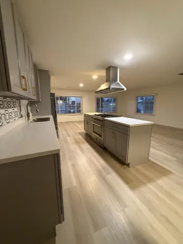 a large kitchen with stainless steel appliances a large counter top a stove a chimney a sink and dishwasher