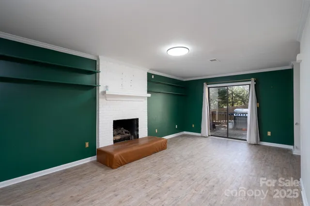 a view of a livingroom with wooden floor a fireplace and window