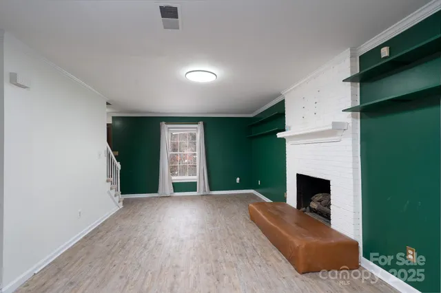 a view of empty room with fireplace and wooden floor