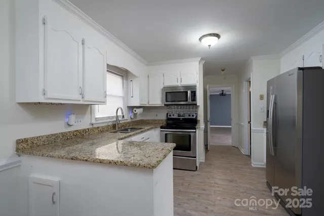 a kitchen with granite countertop a refrigerator and a stove top oven