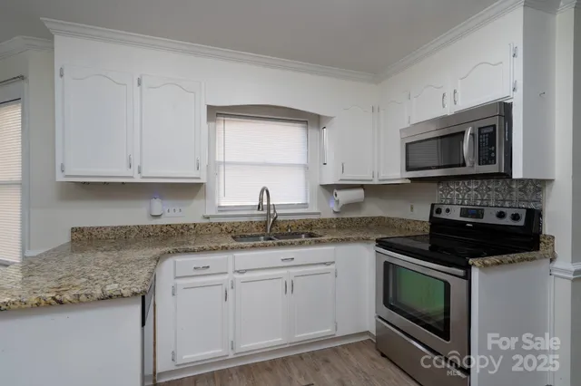 a kitchen with granite countertop white cabinets appliances and a sink