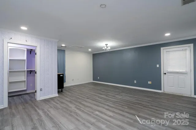a view of an empty room with wooden floor and closet