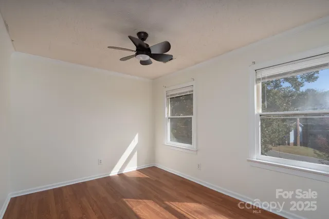 a view of an empty room with a window and wooden floor