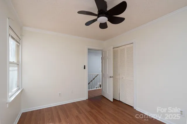 an empty room with wooden floor and a ceiling fan