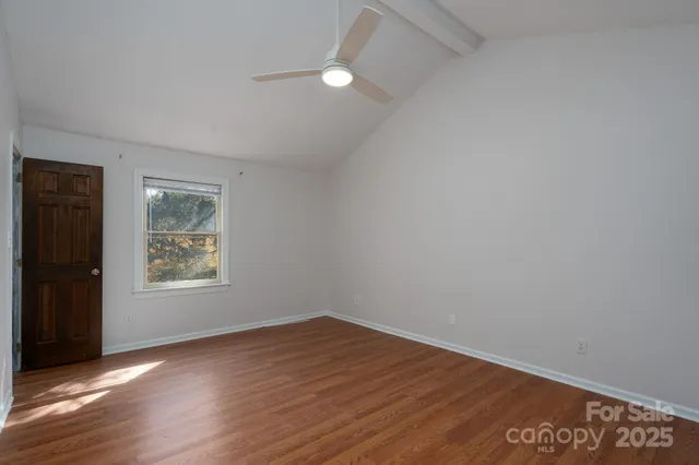 an empty room with wooden floor and window