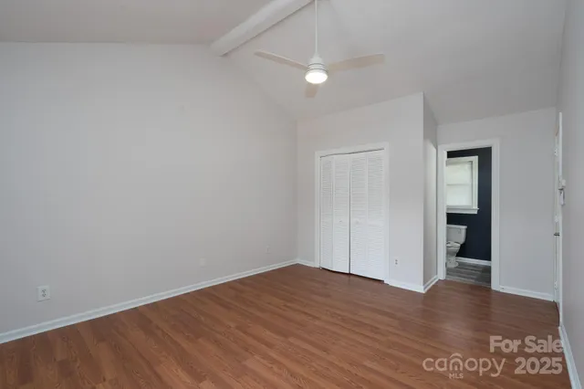 a view of an empty room with wooden floor and closet