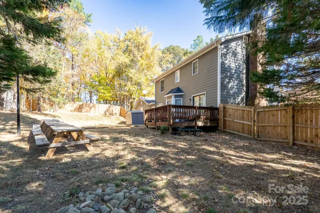 a view of backyard with wooden fence and a large tree