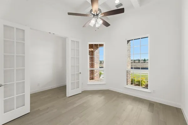 an empty room with windows and fan