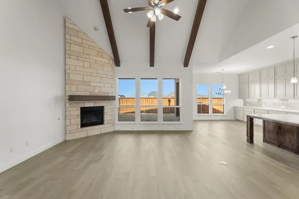 an empty room with wooden floor fireplace and windows