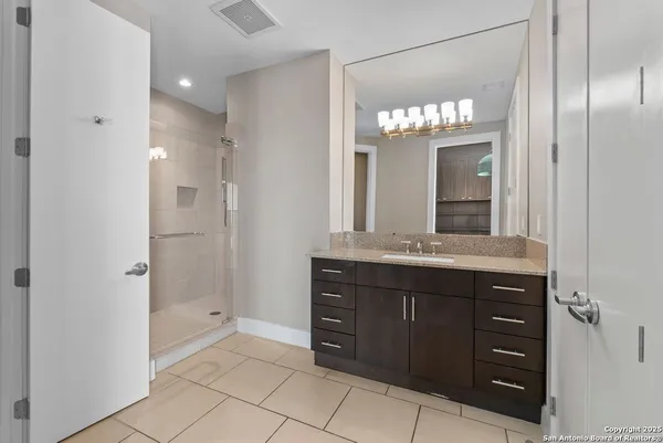 a bathroom with a granite countertop sink a large mirror and a shower