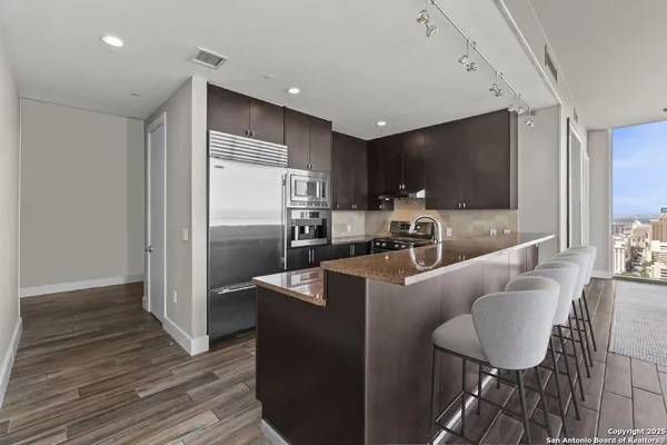 a living room with furniture a flat screen tv and kitchen view