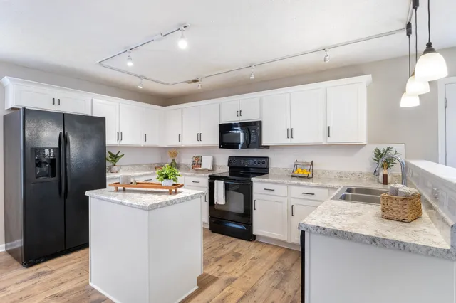 a kitchen with stainless steel appliances granite countertop a refrigerator stove a sink dishwasher and a refrigerator with wooden floor