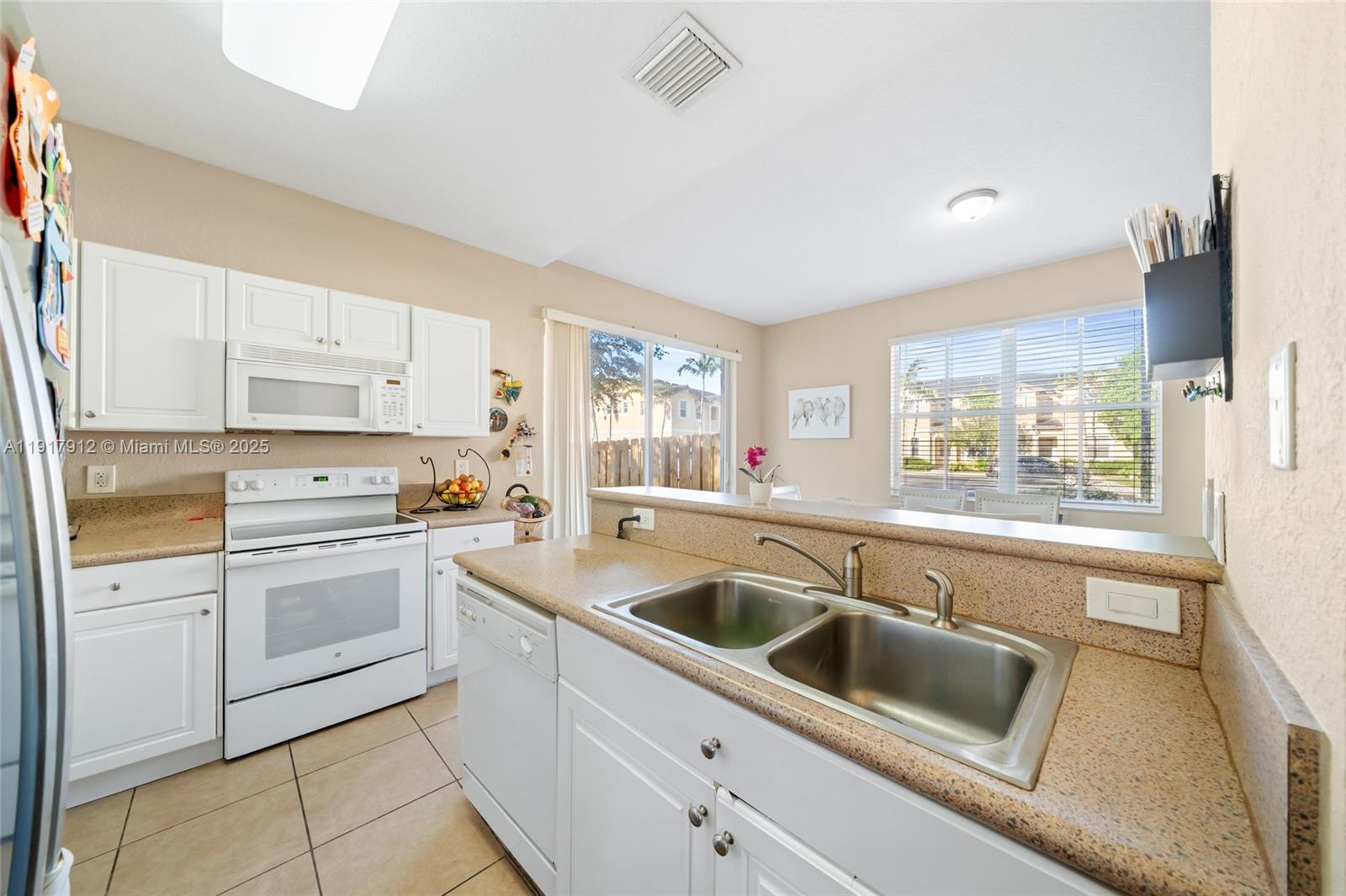 152 Southeast 29th Avenue, Unit 9 Homestead, FL 33033 - Photo 9 of 26 a kitchen with granite countertop white cabinets and white appliances