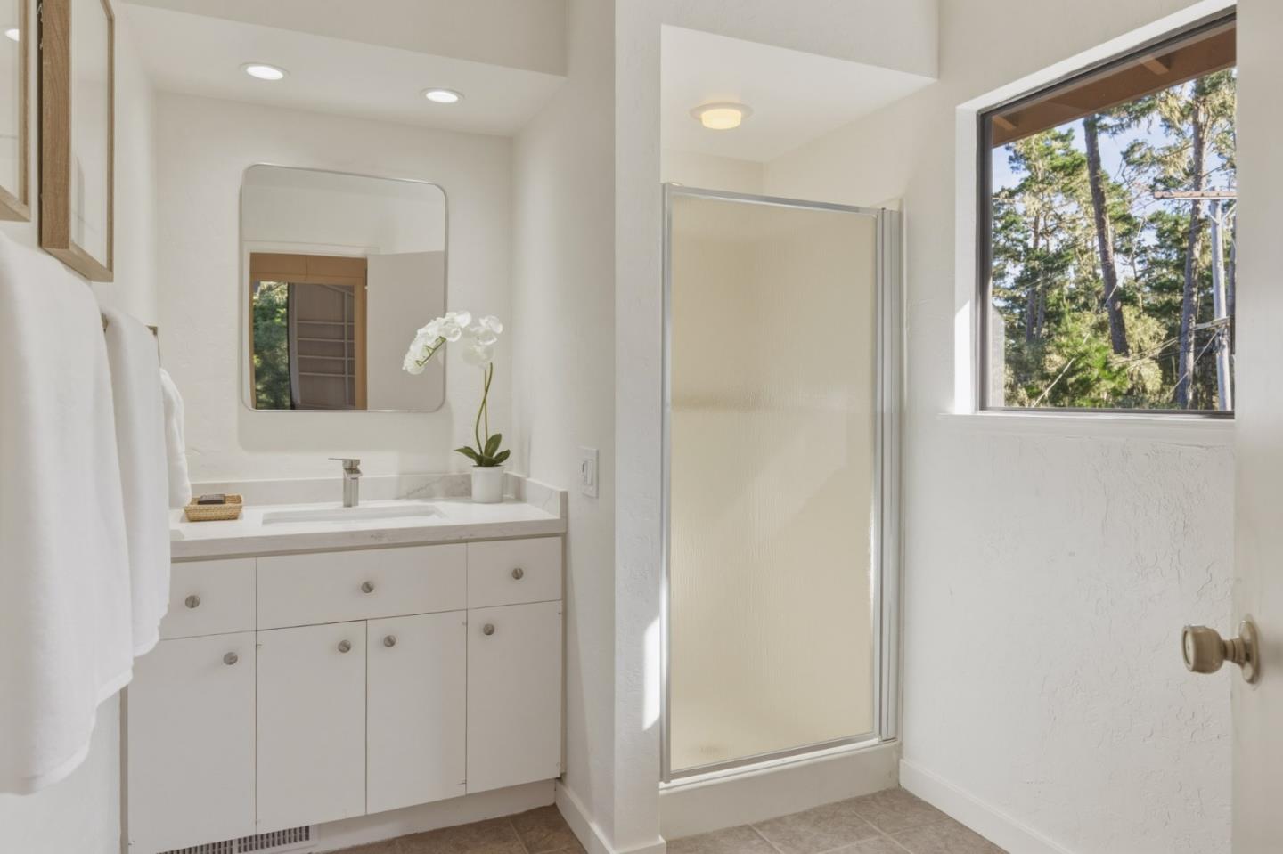 1171 Chaparral Road Pebble Beach, CA 93953 - Photo 20 of 20 a bathroom with a double vanity sink a mirror and next to a window