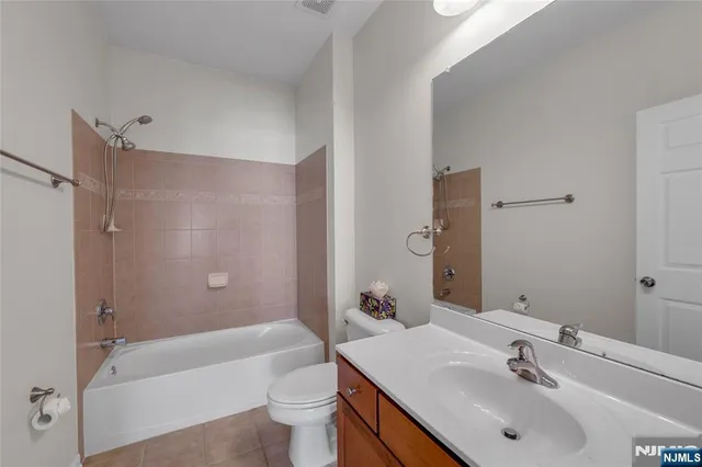 a bathroom with a bathtub shower sink vanity mirror and toilet