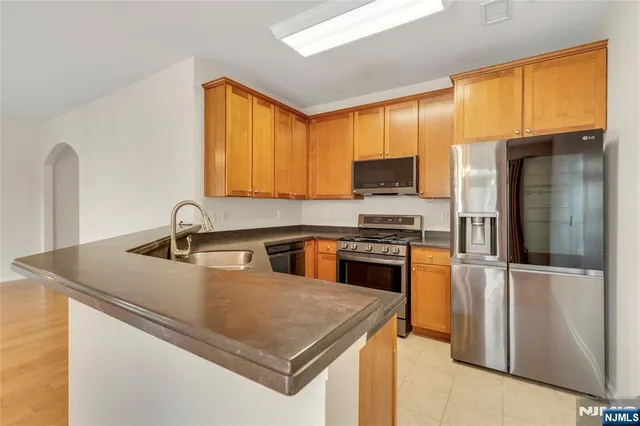 a kitchen with stainless steel appliances granite countertop a sink a stove and a refrigerator