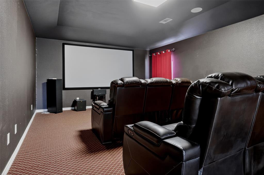 8728 Maple Ridge Trail Fort Worth, TX 76244 - Photo 6 of 40 Dedicated media room featuring a large projection screen, dark textured walls, and patterned carpet flooring