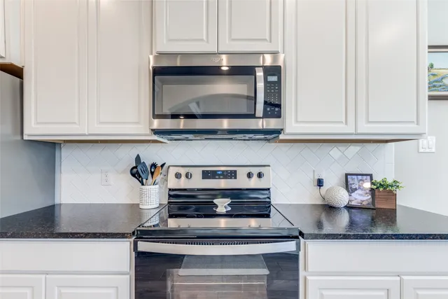 a kitchen with granite countertop white cabinets and a stove