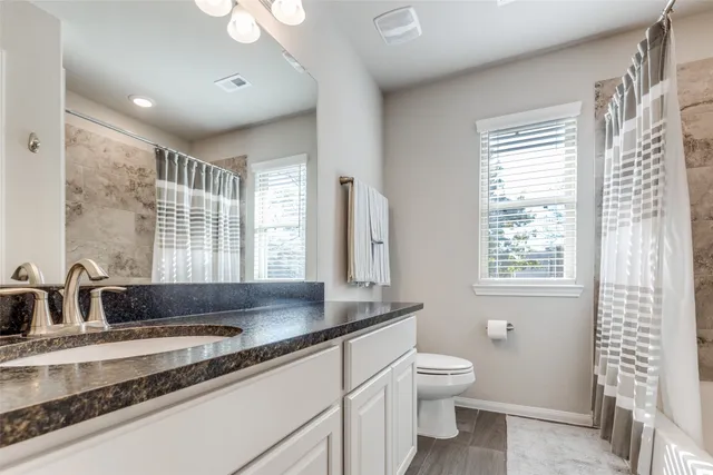 a bathroom with a double vanity sink toilet and a tub