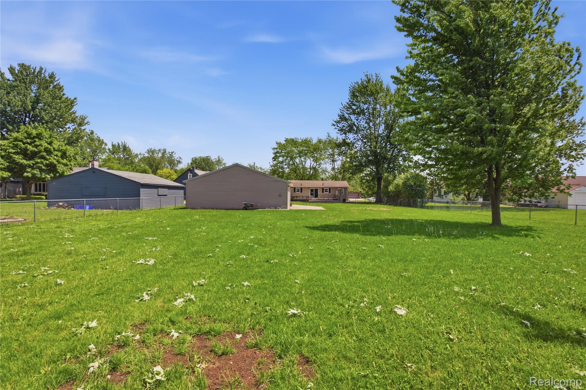 37257 Dundee Street Sterling Heights, MI 48310 - Photo 39 of 47 Expansive green lawn with mature trees and partial chain-link fencing