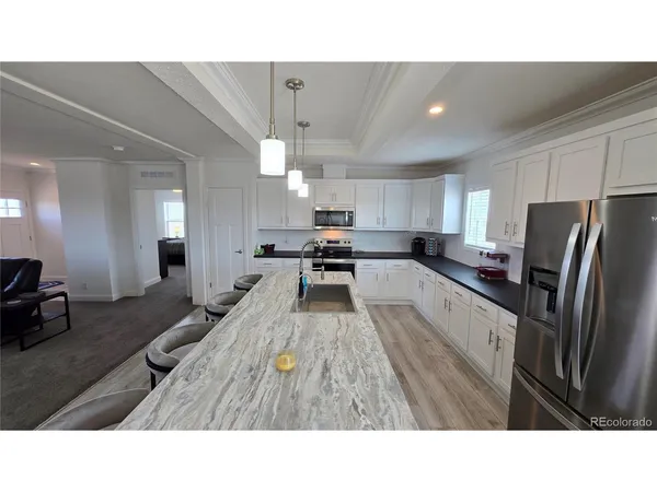 a kitchen with kitchen island a counter top space a sink stainless steel appliances and cabinets