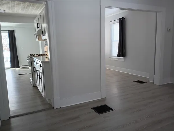 a view of an empty room with wooden floor and a window