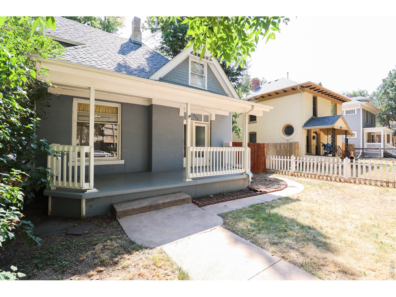 608 South Howes Street Fort Collins, CO 80521 - Photo 3 of 28 a view of a white house with a small yard and wooden fence