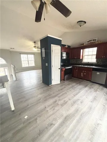 a kitchen with stainless steel appliances a refrigerator a stove a sink dishwasher and a dining table with wooden floor