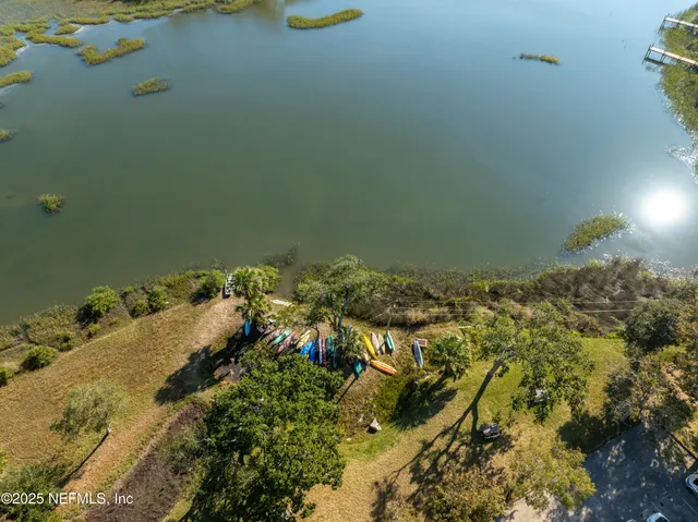 a view of a lake with lawn chairs under an umbrella