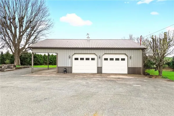 a view of house with a big yard and large trees